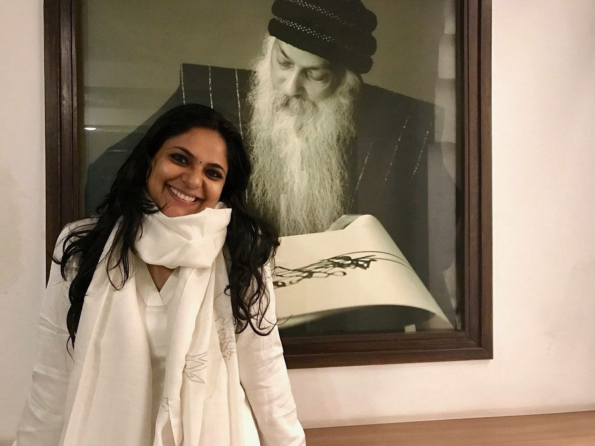 The author of this piece, Richa Anirudh, posing next to a picture of her guru, Osho Rajneesh.