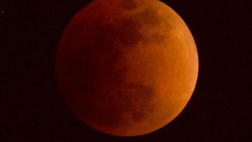 The moon turns a reddish hue as it passes through the Earth’s shadow during a lunar eclipse.