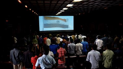People stand for the national anthem at a movie hall.&nbsp;