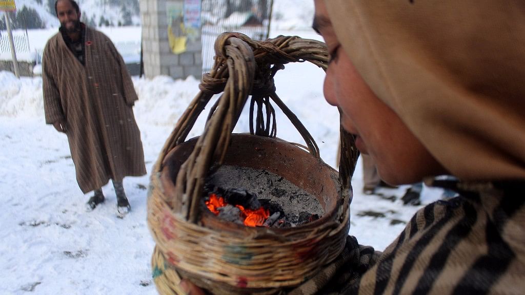 A boy blows a <i>kangri –</i> the traditional fire pot used by Kashmiris during winter to keep themselves warm.&nbsp;