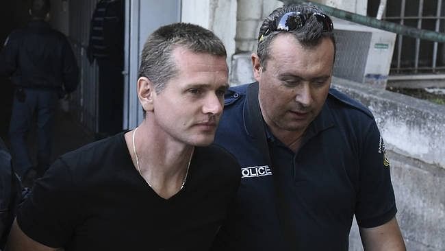Alexander Vinnik, a 38 year old Russian man (left) suspected of running a money laundering operation, is escorted by a plain-clothes police officer to a court.