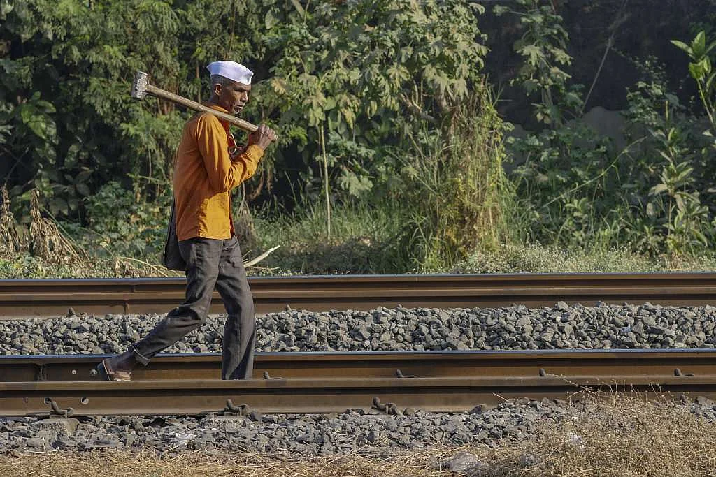 A worker carries a sledgehammer as he walks along rail tracks in Mumbai. 