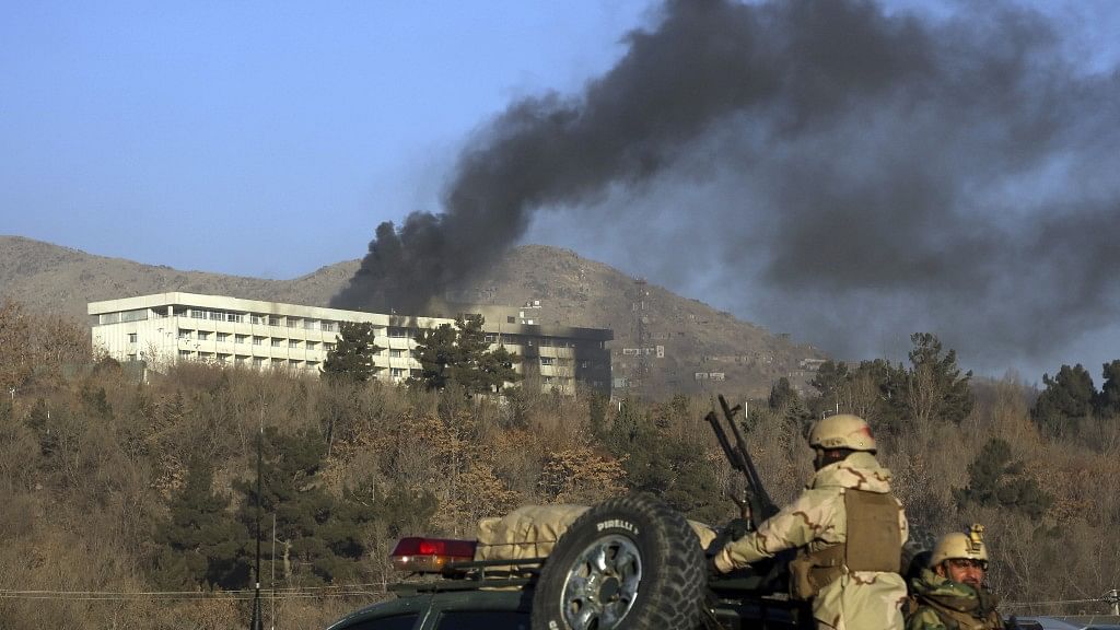 Afghan security personnel stand guard as black smoke rises from the Intercontinental Hotel after an attack in Kabul.&nbsp;