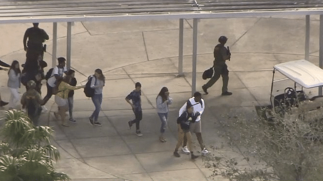 Live television showed dozens of students running and walking away from the school, weaving their way between large numbers of emergency vehicles including police cars, ambulances and fire trucks.