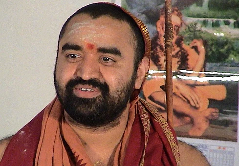 A member is pursuing to book a case against Kanchi Acharya Vijayendra Saraswati for not having stood up when the State song.