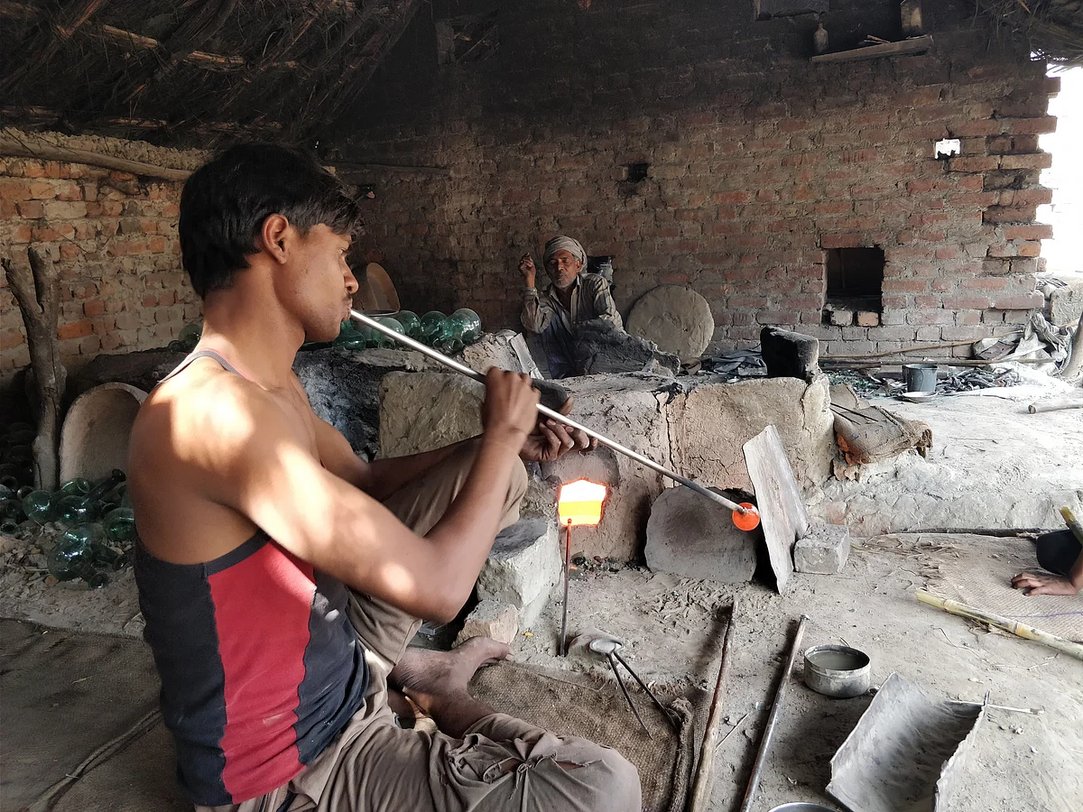 A man is seen blowing into the pipe to make gangajali.