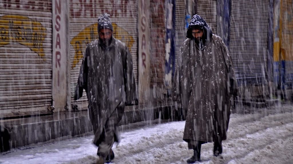 Two men walk in heavy snow in Srinagar.