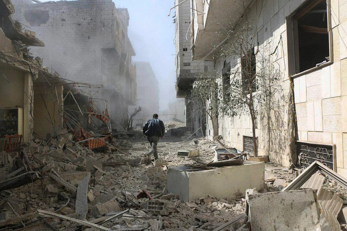 A Syrian man runs between buildings destroyed in airstrikes and shelling by Syrian government forces, in Ghouta, Syria. 