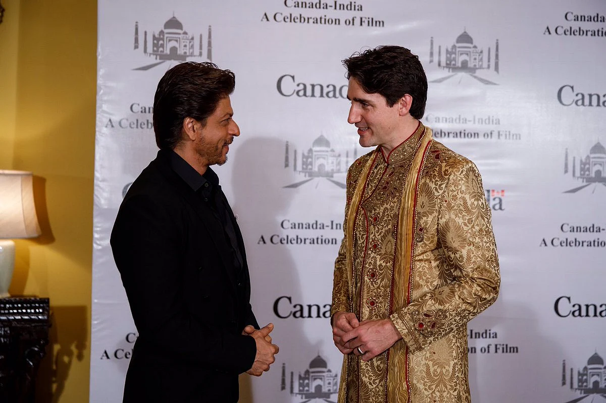 Shah Rukh Khan greets Justin Trudeau, who glistens in gold.