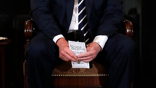 President Donald Trump holds notes during a listening session with high school students and teachers in the State Dining Room of the White House in Washington, Wednesday, 21 February 2018.