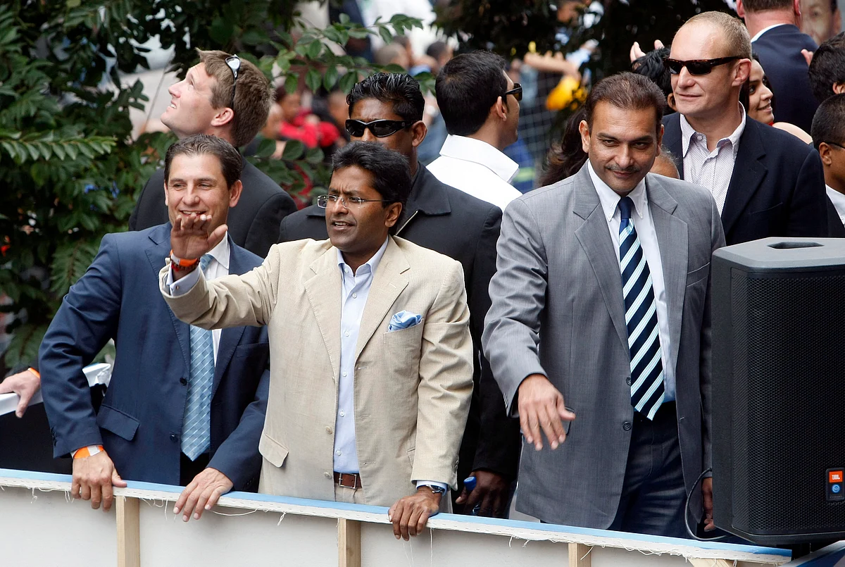 Chairman of the Indian Premier League (IPL) Lalit Modi (C) and and former cricketer Ravi Shastri (R) wave to crowds during a street parade by teams competing in the IPL in Cape Town in 2009.