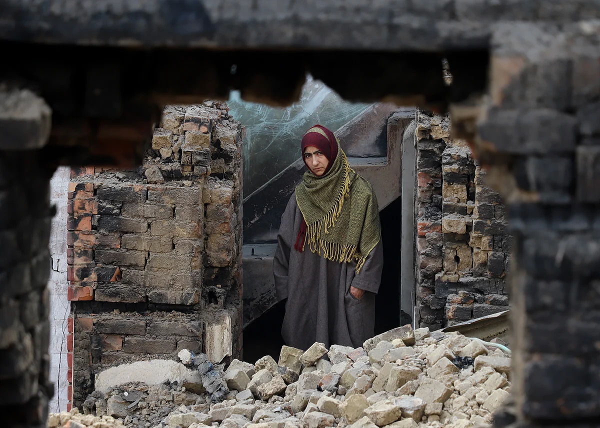 Ghulam’s neighbour looks over from the remains of his house. 