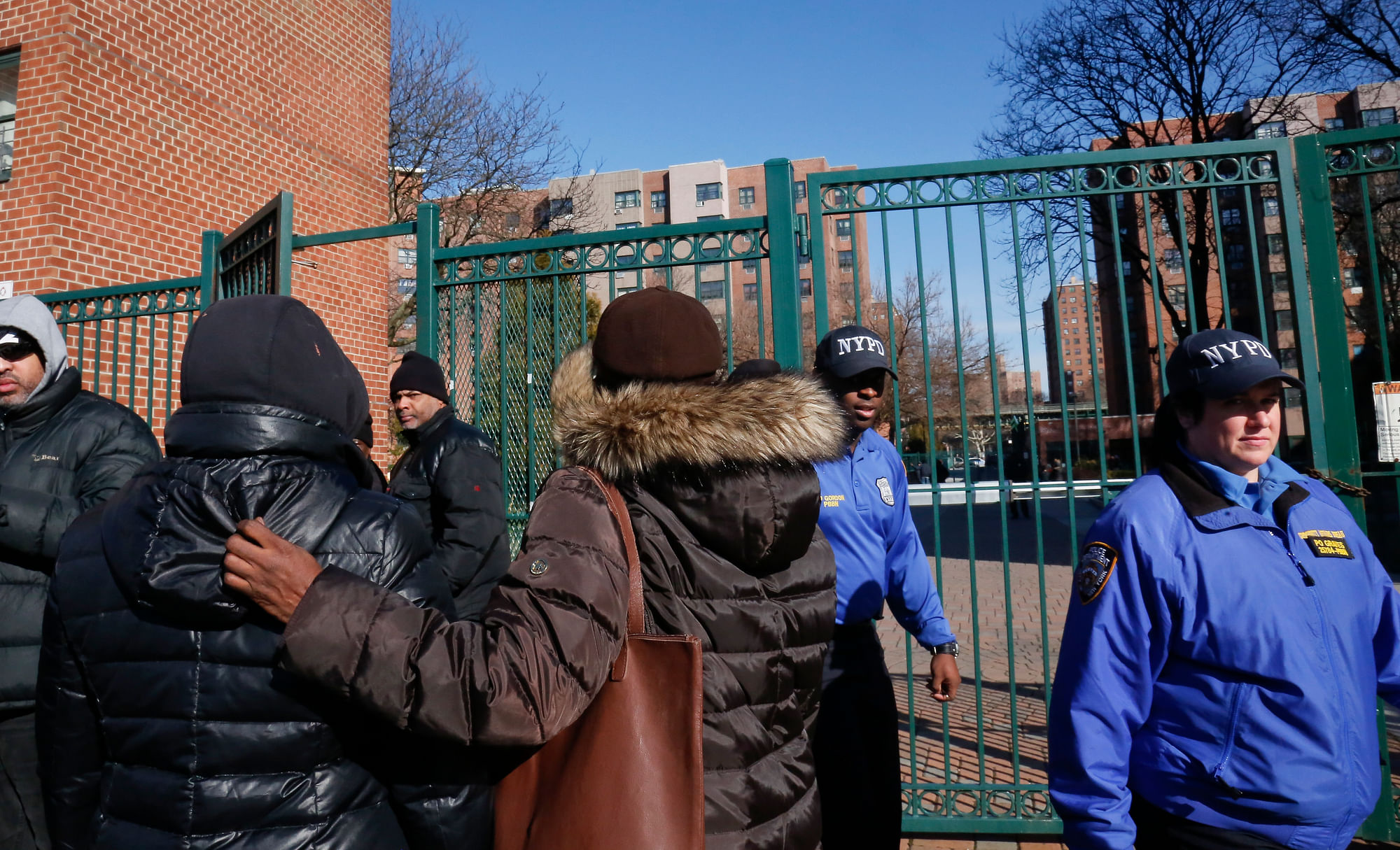 Neighbors gather outside the apartment in New York, where four people, including a young child, were found shot to death on 14 March.
