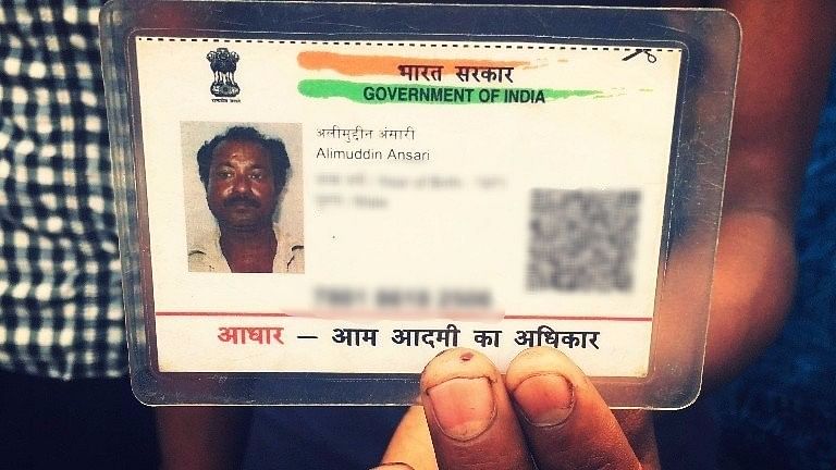 Alimuddin Ansari’s son holds up the only photograph he has of his father, his Aadhaar card. (Photo: Aishwarya S Iyer/<b>The Quint</b>)