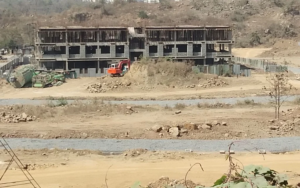 Roads and a partially built school building at the relocation site.