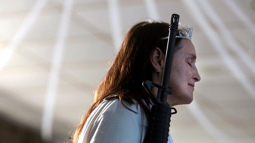 A standing woman closes her eyes as she holds an unloaded weapon during services at the World Peace and Unification Sanctuary.