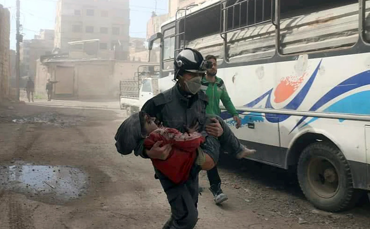 Syrian Civil Defense group carrying a boy who was wounded during airstrikes and shelling by Syrian government forces in Ghouta