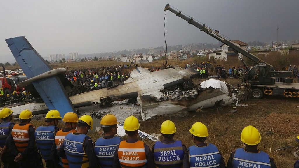 Nepalese rescuers and police are seen near the debris after a passenger plane from Bangladesh crashed at the airport in Kathmandu, Nepal on 12 March.