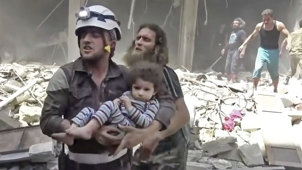 A civil defense worker carries a child after airstrikes hit Aleppo in Syria | File