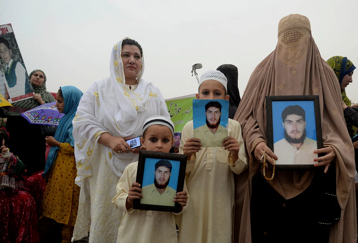 In this Sunday, 8 April 2018 file photo, a Pashtun family from a Pakistani tribal area display pictures of a missing family member during a Pashtun Protection Movement rally in Peshawar, Pakistan