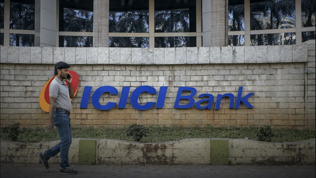 A man walking past an  ICICI Bank.