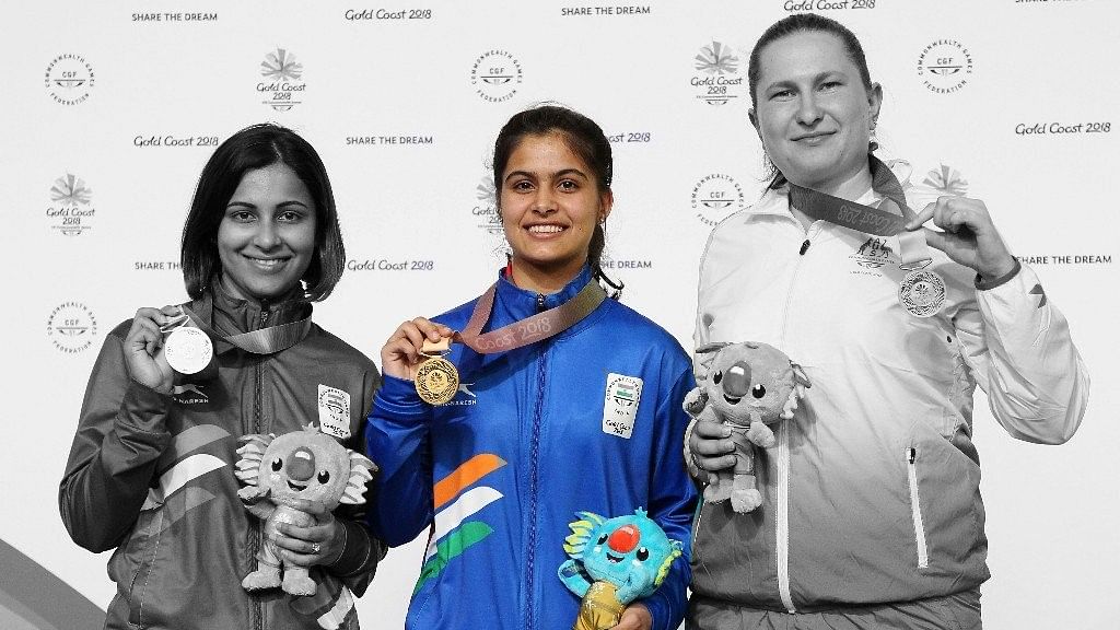 Manu Bhaker of India, center, poses with the gold medal, accompanied by silver medalist Sidhu Heena of India, left, and bronze medalist Elena Galiabovitch of Australia, right.