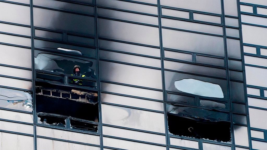 A firefighter looks out from the window of a damaged apartment in Trump Towers in New York on Saturday.