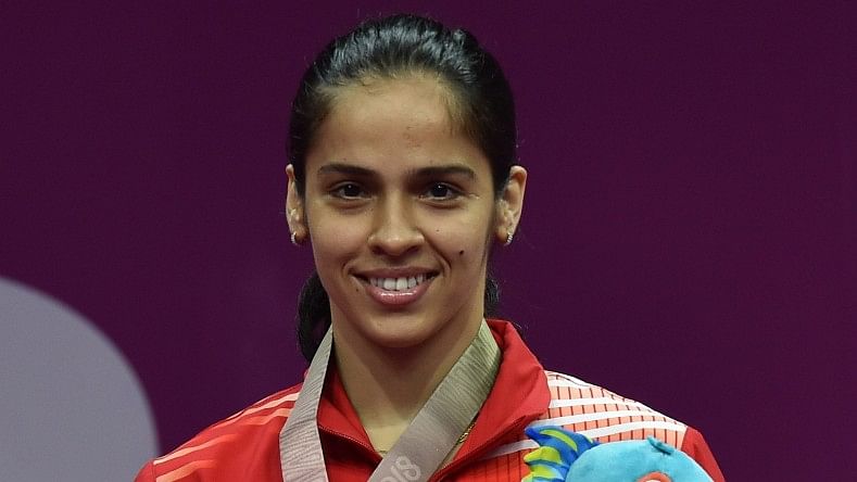 Saina Nehwal stands at the podium after winning the gold medal in the singles competition.