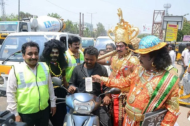 Actor playing Chitragupta hands over a receipt of a fine levied to a commuter