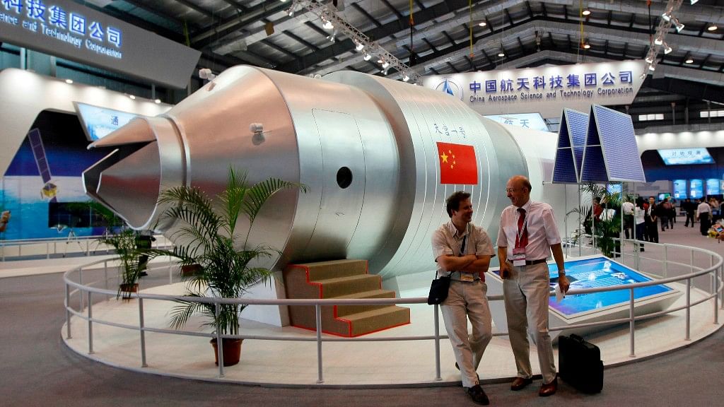 In this 16 November 2010 file photo, visitors sit beside a model of China’s Tiangong-1 space station at the 8th China International Aviation and Aerospace Exhibition in Zhuhai in southern China’s Guangdong Province.&nbsp;