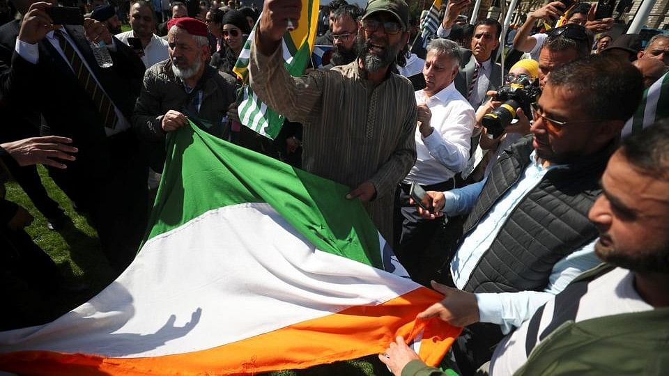 Protesters rip up India’s flag after tearing it off a flagpole in Parliament Square, London, on 18 April.&nbsp;