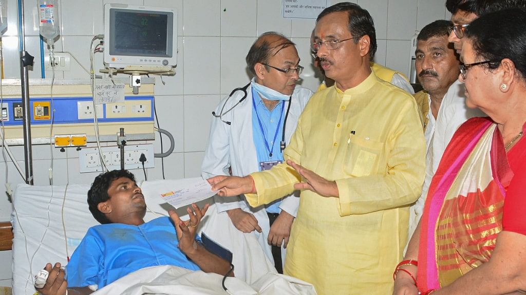 UP deputy CM Dinesh Sharma hands over a cheque to a man who fell ill after allegedly consuming spurious liquor on Saturday, 19 May.