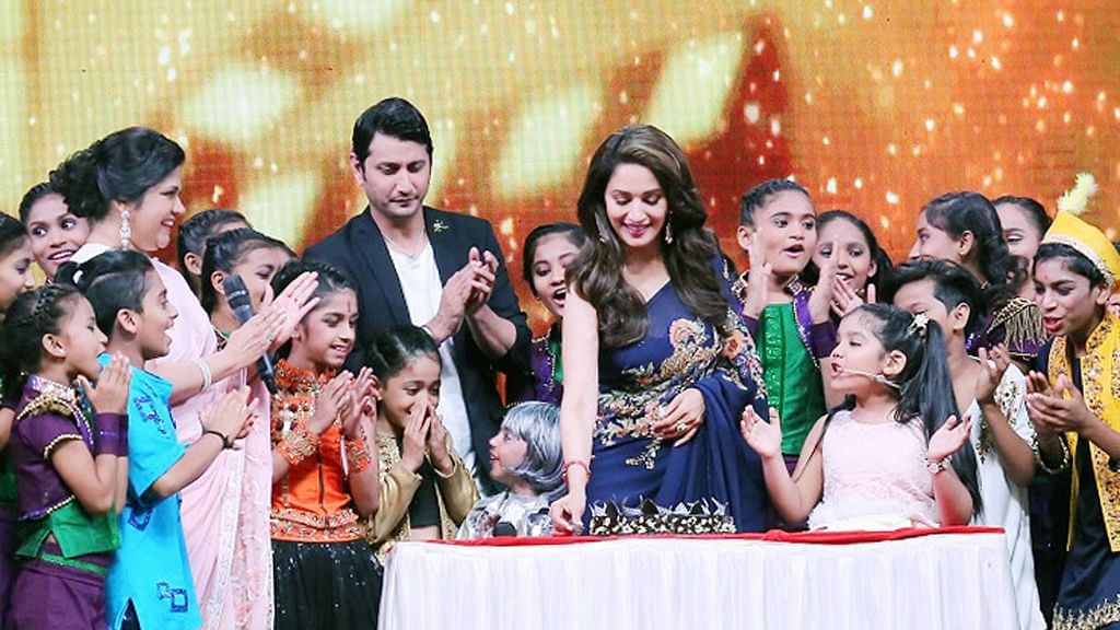 Madhuri Dixit cuts a birthday cake with Renuka Shahane (left) and the participants of <em>DID Lil Masters.</em>&nbsp;