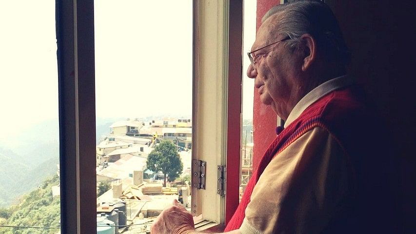 Ruskin Bond stands, watching the mountains outside his home in the hills.