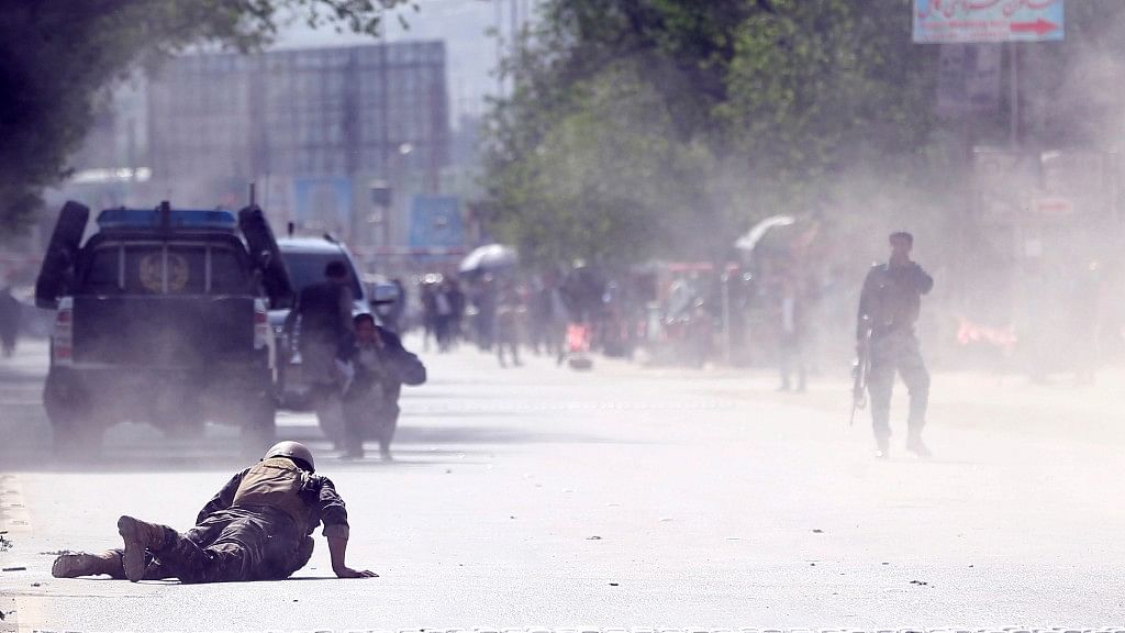 A security force and a civilian lie low at the site of a suicide attack after the second bombing in Kabul, Afghanistan.