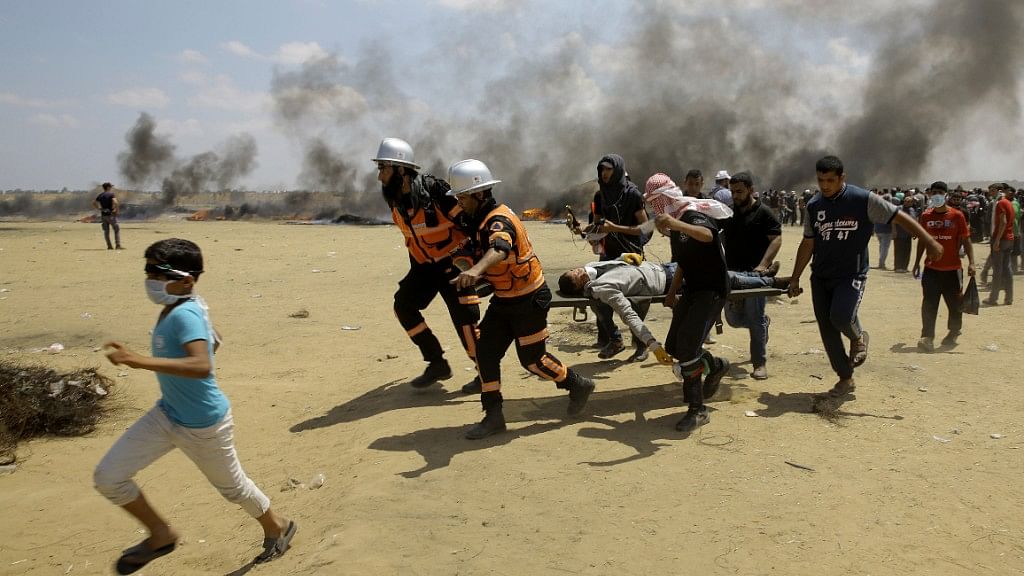 Palestinian medics and protesters evacuate a wounded youth during a protest at the Gaza Strip’s border with Israel.