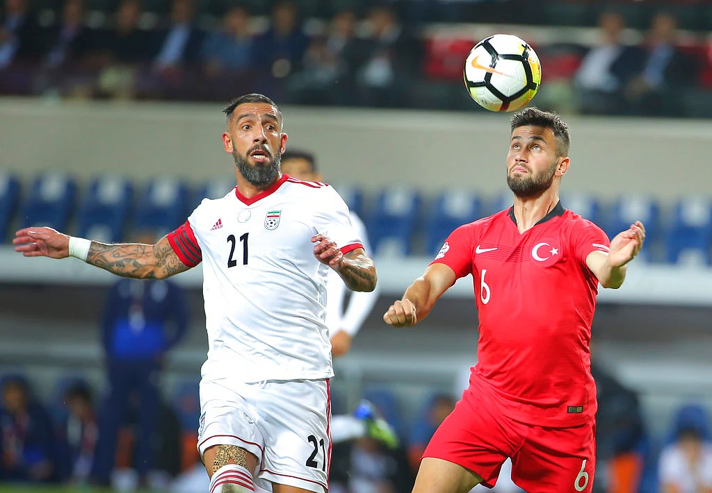 Turkey’s Omer Bayram, right, controls the ball as Iran’s Ashkan Dejagah, left, tries to stop him.