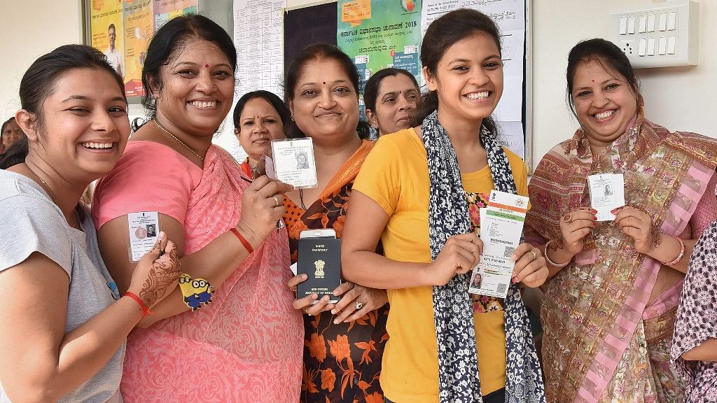 Voters show their voting ID as they cast their vote for Karnataka Assembly elections in Hubballi on Saturday.