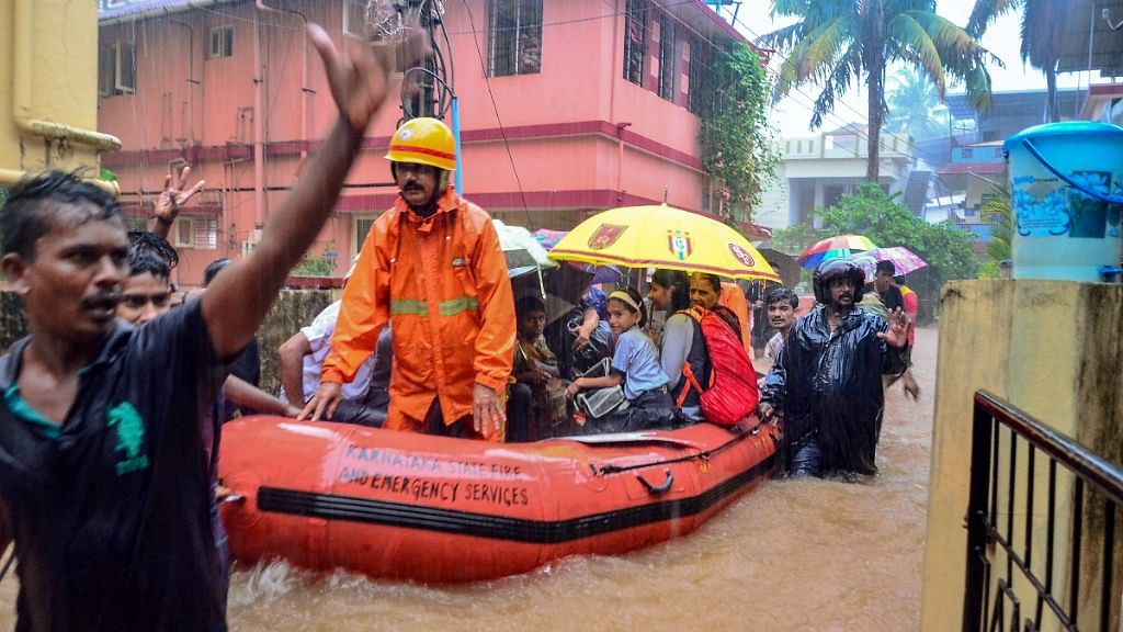 Rescuers shift people to a safer place from a flooded locality, after a thunderstorm, in Mangaluru.
