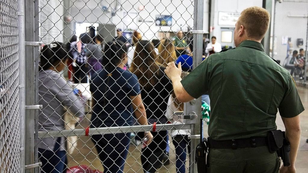 A US Border Patrol agent watches as people who’ve been taken into custody related to cases of illegal entry into the United States, stand in line at a facility in McAllen, Texas.