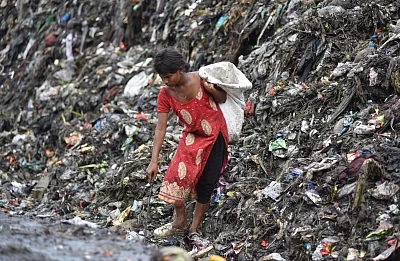 Guwahati : A rag picker seen looking for recyclable items in heaps of garbage at a dump-yard in Guwahati on the eve of World Environment Day, on June 4, 2018. (Photo: IANS)