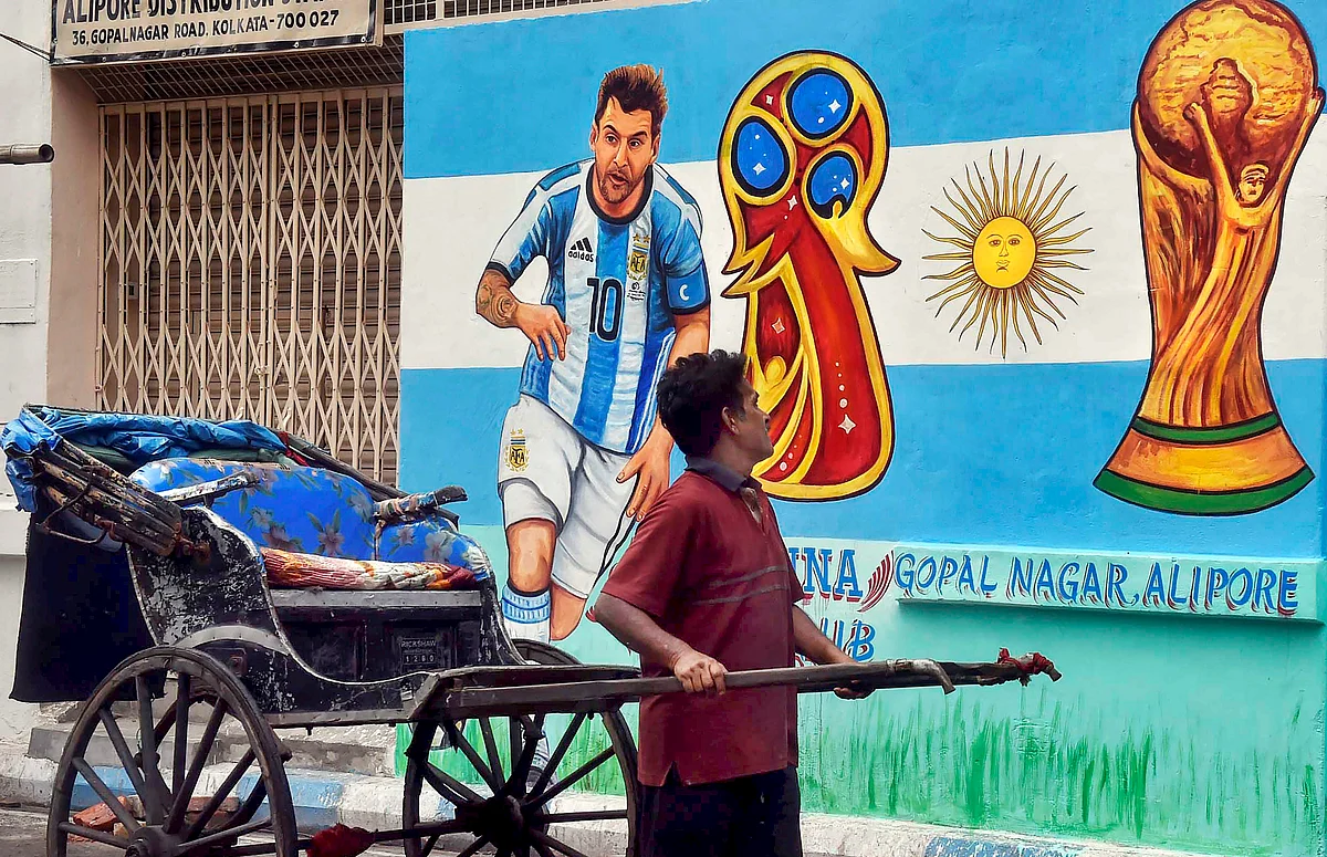 A hand-rickshaw puller moves past a wall painted with graffiti of Argentine footballer Lionel Messi ahead of FIFA World Cup 2018 in Kolkata on Sunday.