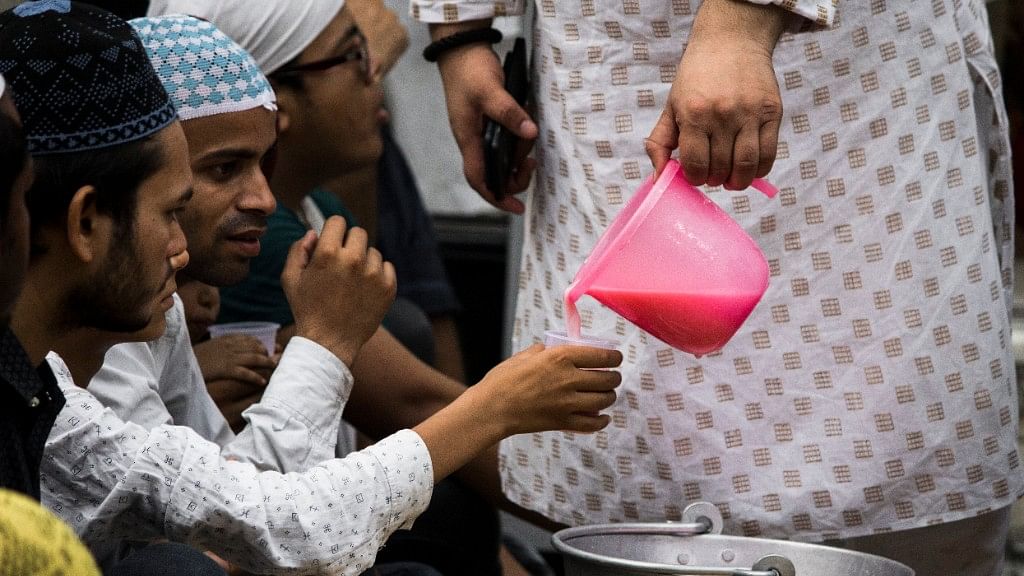Syed Suhail Nizami, a caretaker at the shrine, distributes sweet milk to devotees.