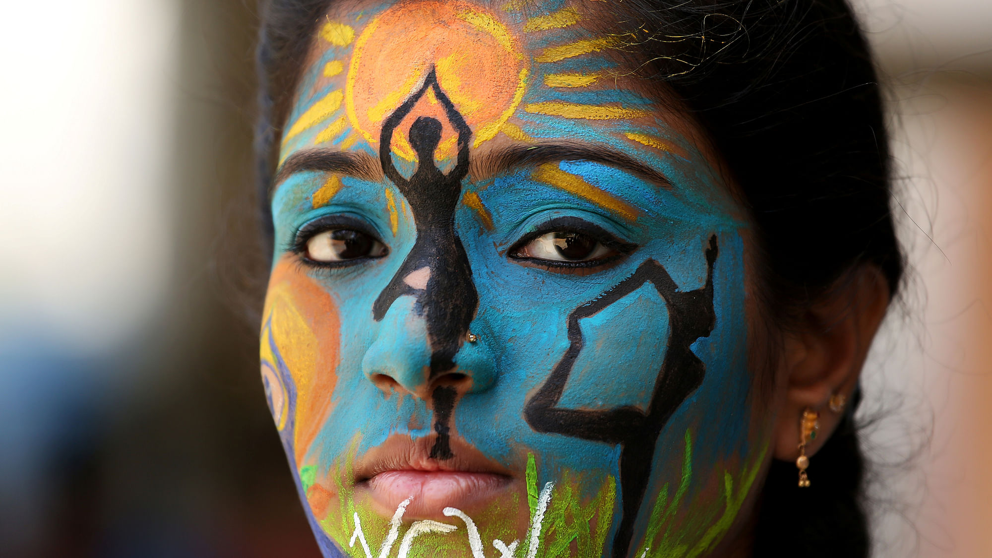 A college student poses as she displays her painted face as an awareness ahead of International Yoga Day, in Chennai, India.