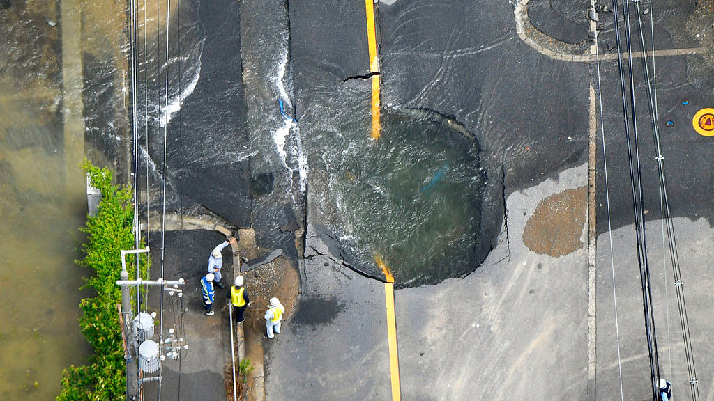 Water floods out from crack in the road, following an earthquake in Takatsuki, Osaka.