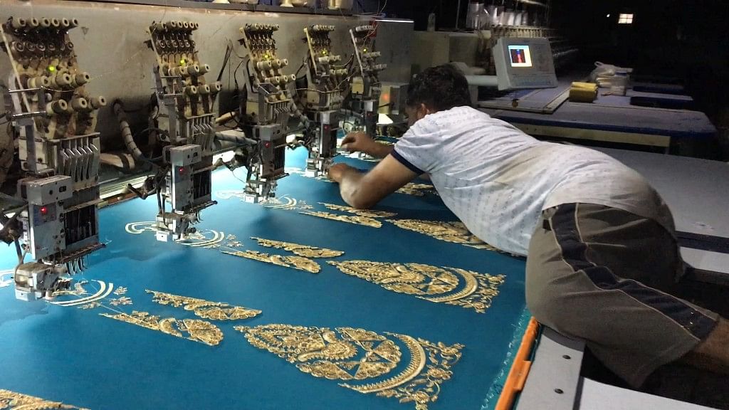 An embroidery worker threads the jari into the needle&nbsp;