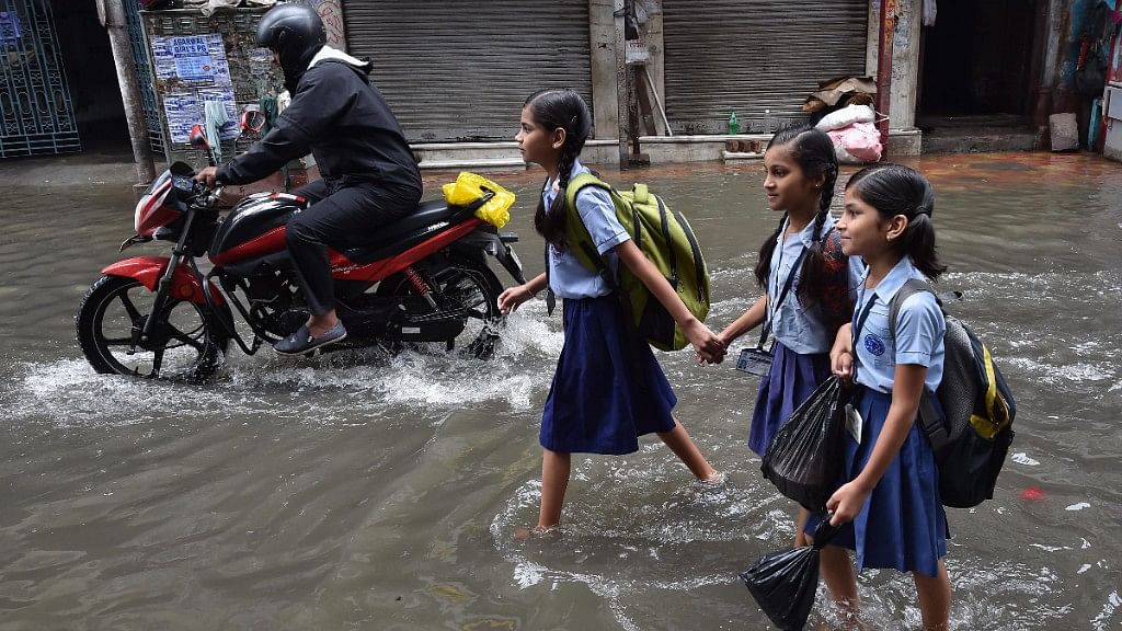 Students wade through a water-logged street after heavy rainfall  in Kolkata on 26 June 2018.