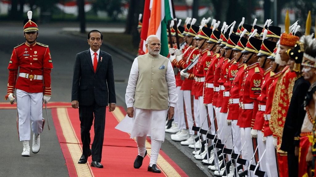 Indian Prime Minister Narendra Modi, third from left, walks past an honor guard, accompanied by Indonesian President Joko Widodo.