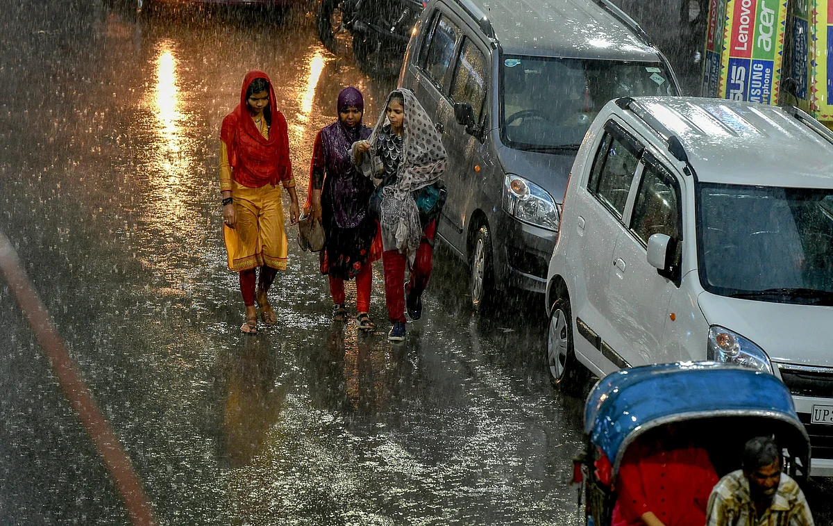 Pedestrians try to make their way across a street during heavy rain, in Lucknow on Tuesday, June 26, 2018.