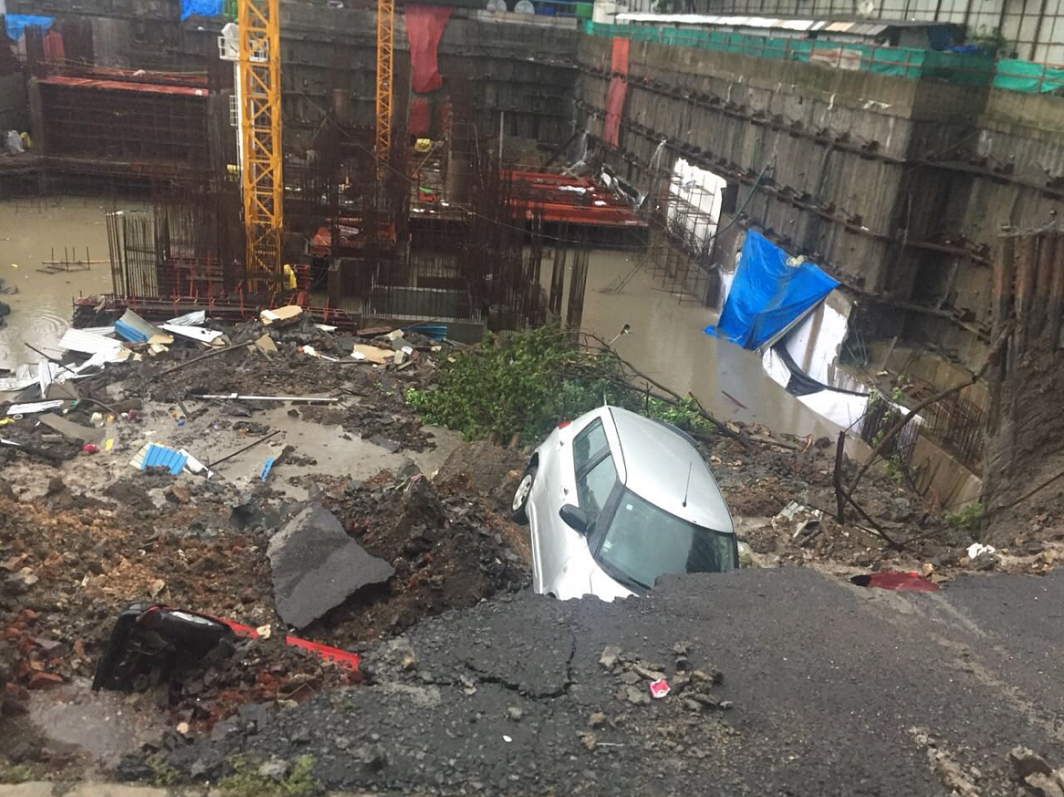 Cars buried under rubble after a wall caved in following heavy rains in Mumbai.
